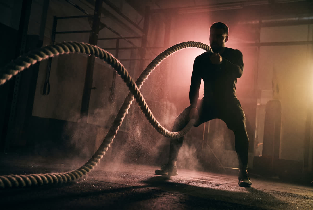 Athlete training with battle ropes in a dark gym